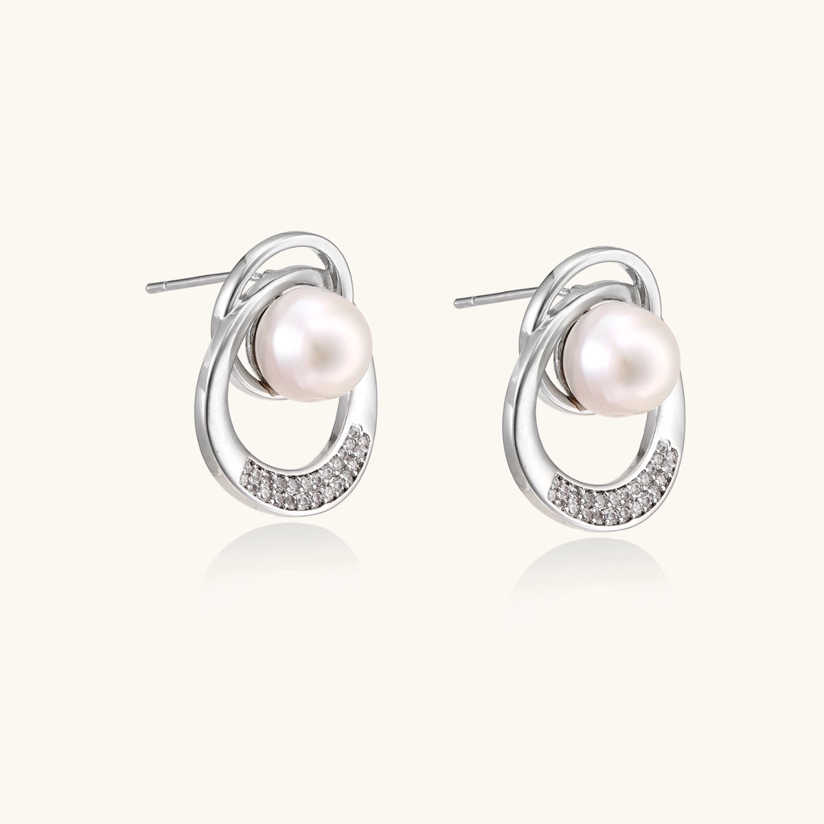 White gold-plated brass earrings with circular design, freshwater pearl center, and diamond accents