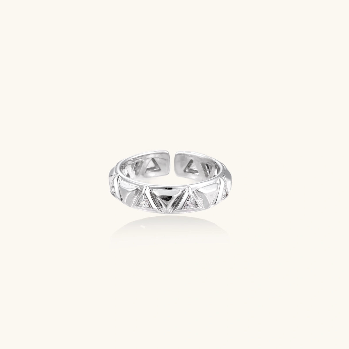 White gold adjustable ring with geometric triangle cutouts and zirconia stones on cream background